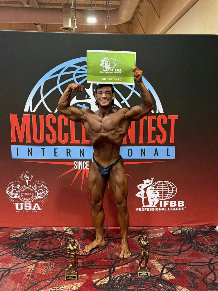 Zack Granly holding his IFBB Pro League card at the 2026 NPC USA Championships