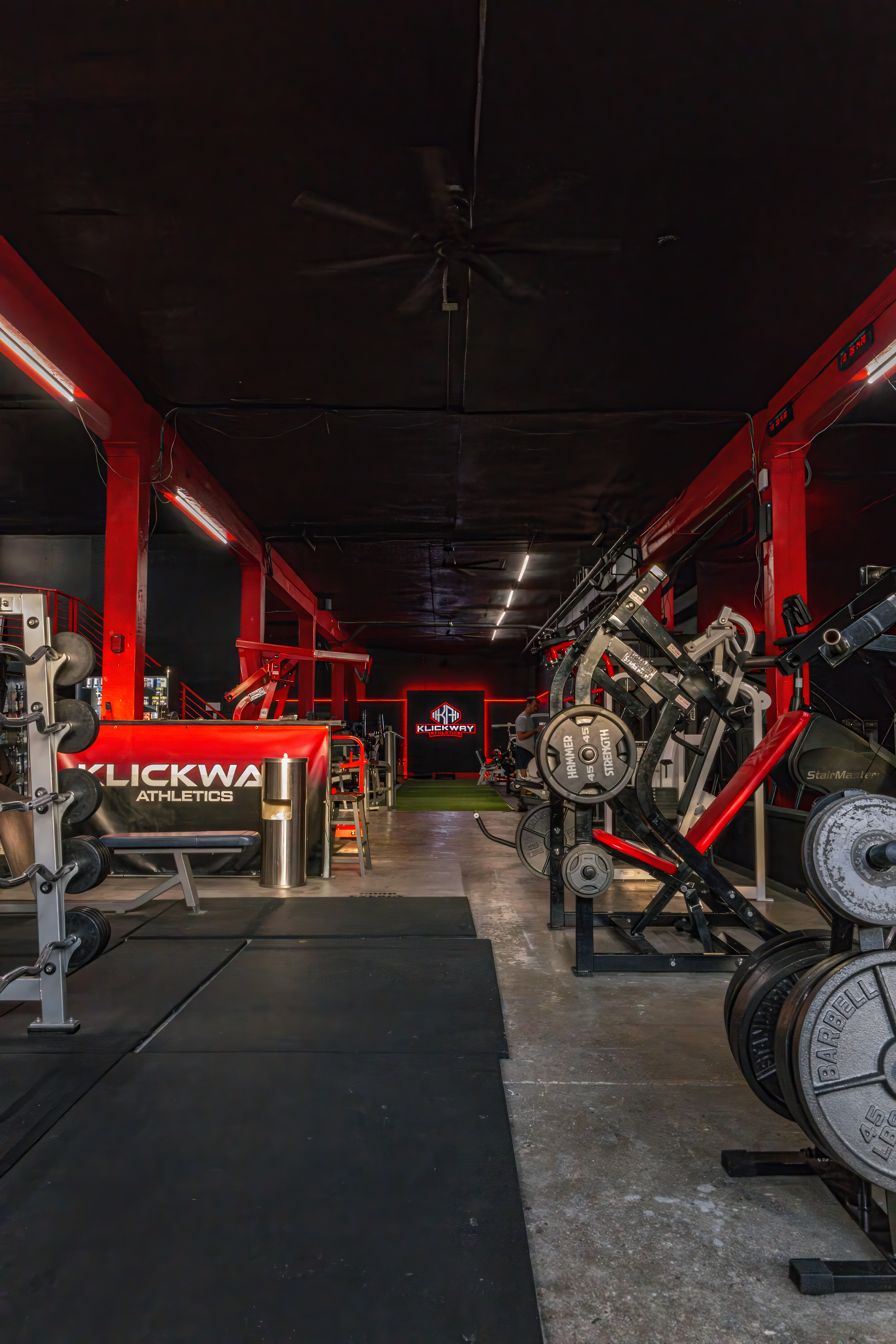 View down the main training area of KlickWay Athletics, highlighting the expansive layout, high ceilings, and diverse array of weightlifting machines and free weights