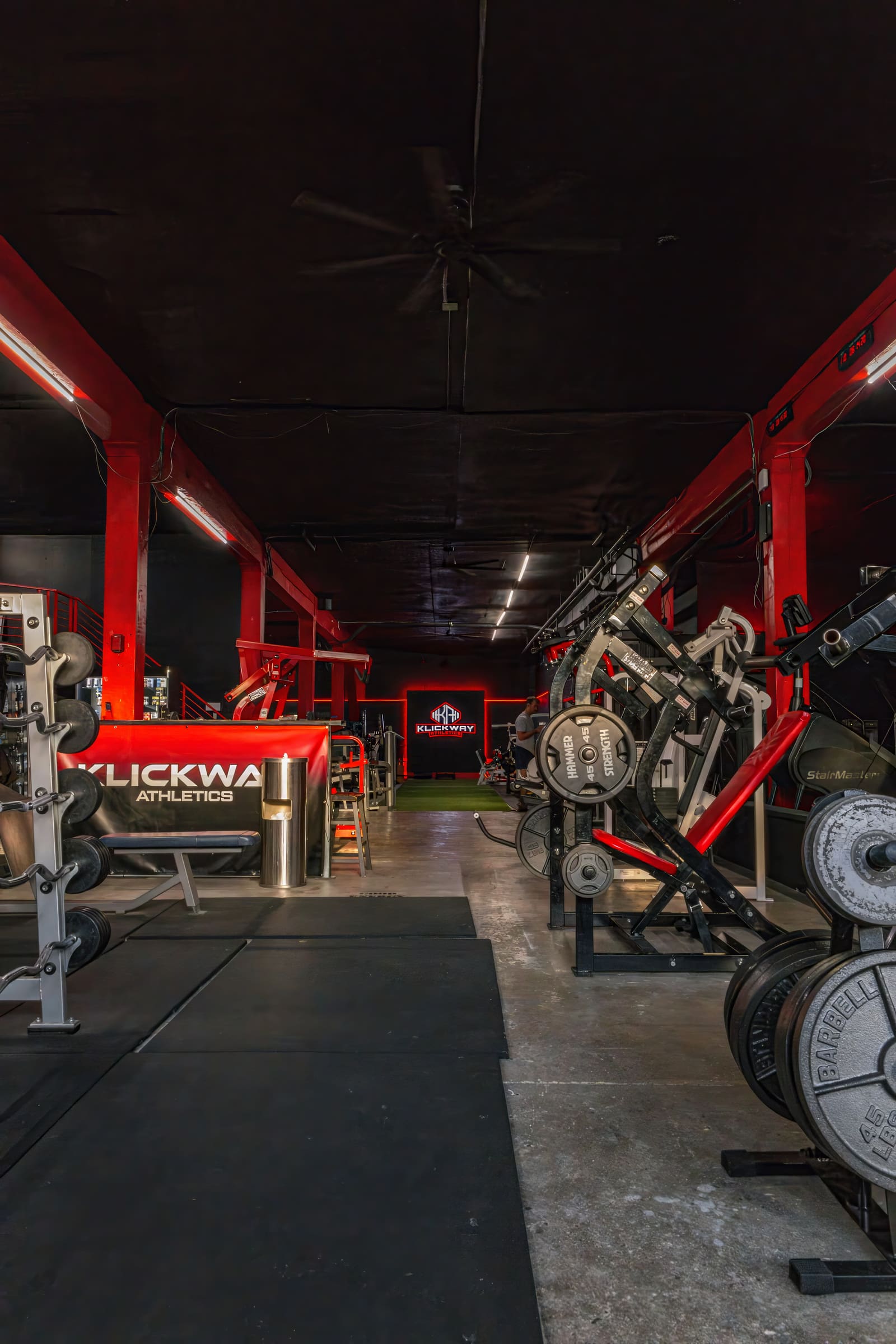 View down the main training area of KlickWay Athletics, highlighting the expansive layout, high ceilings, and diverse array of weightlifting machines and free weights