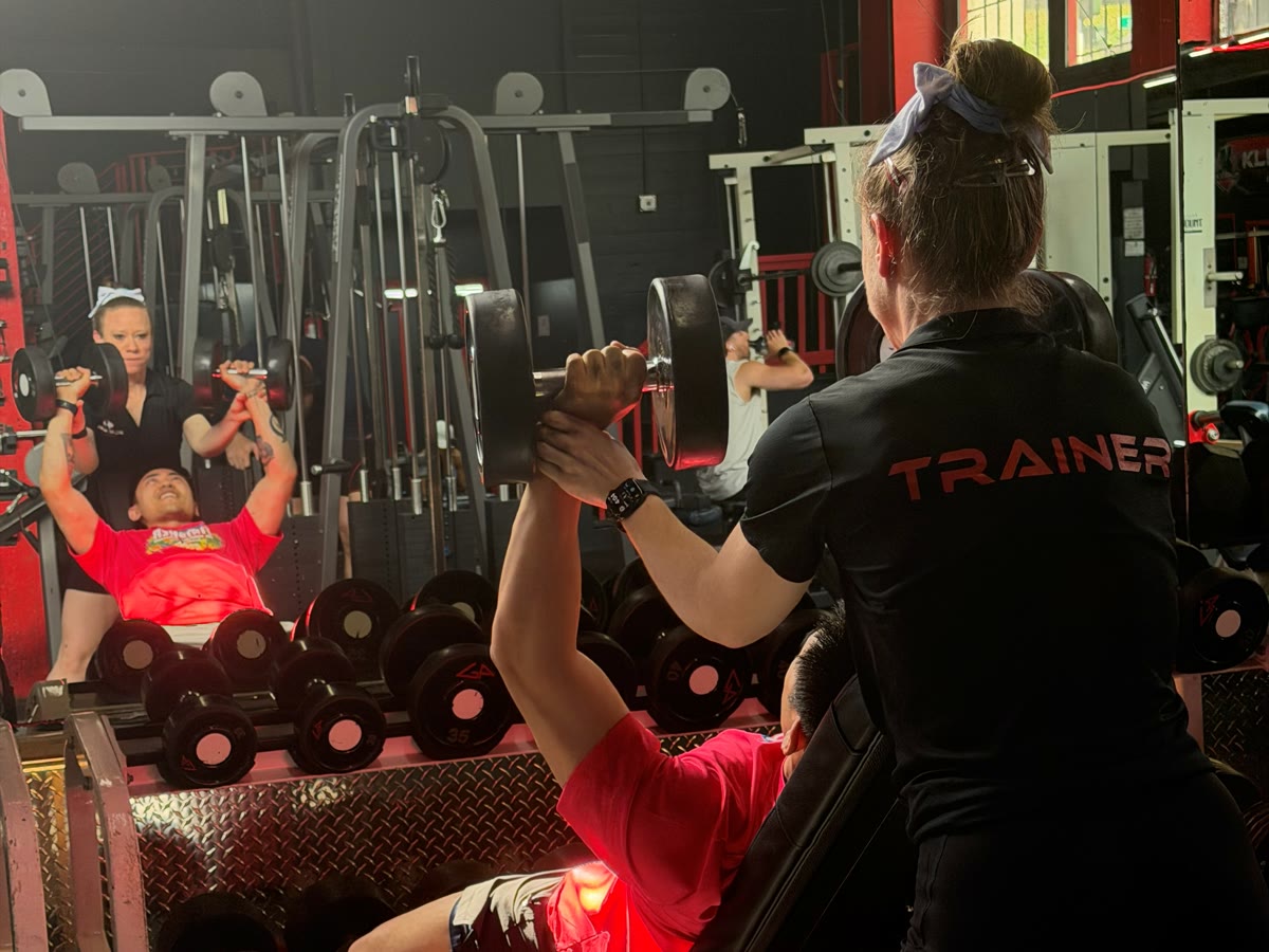 KlickWay trainer spotting a client through an incline dumbbell press