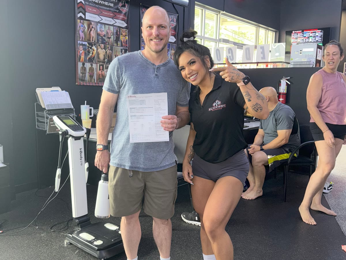 Nutrition coaching client holding his InBody results next to coach Yohannah at the front desk
